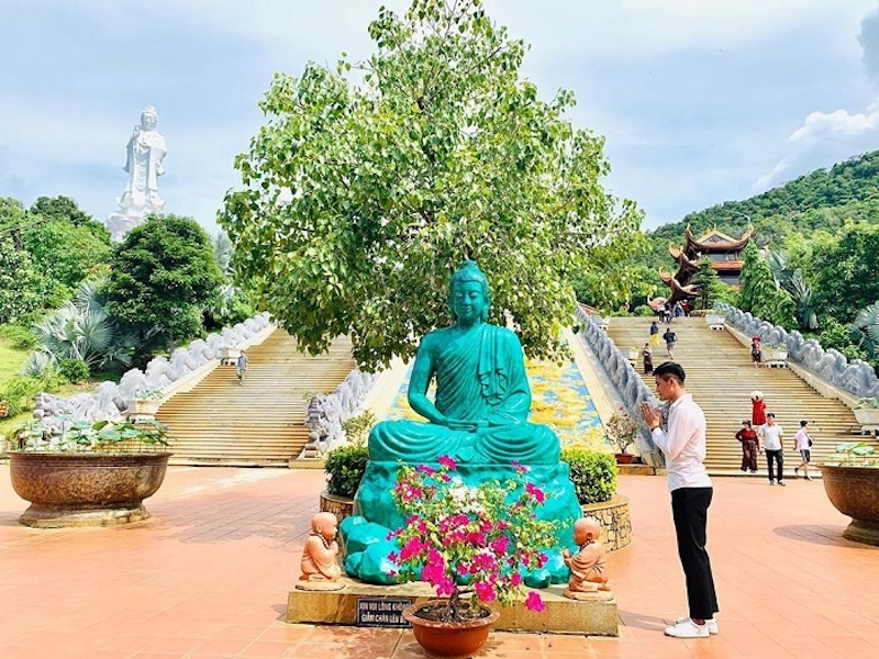 A person is showing his respect to the Buddha statue at ho quoc pagoda phu quoc
