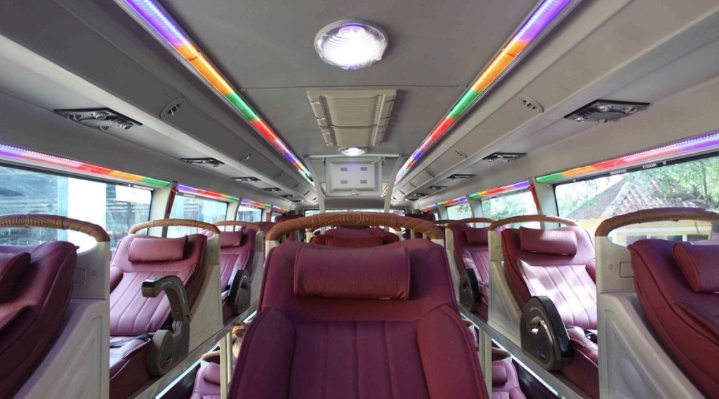 The sleeper bus cabin features red leather seats and multi-colored LED lights on the ceiling