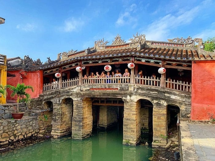 The Japanese Covered Bridge in Hoi An, a wooden bridge with a pagoda on top, surrounded by yellow walls and green plants