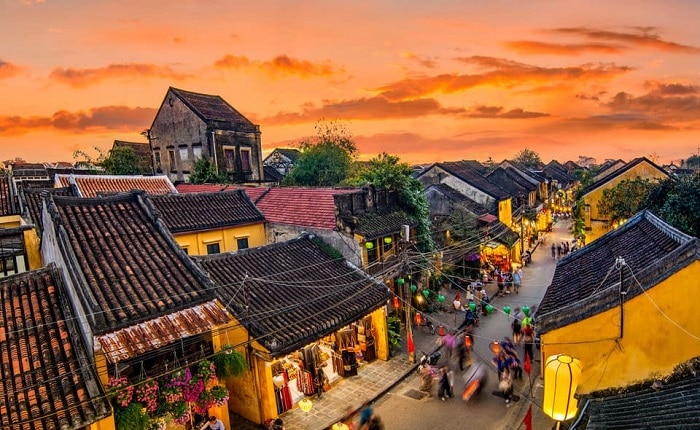 Hoi An old street during the day with yellow walls, colorful lanterns hanging above